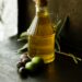 bouteille d'huile d'olive sur table en bois avec olives