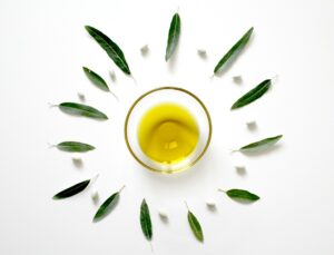coupelle avec de l'huile d'olive non filtrée avec des feuilles autour en forme de soleil
